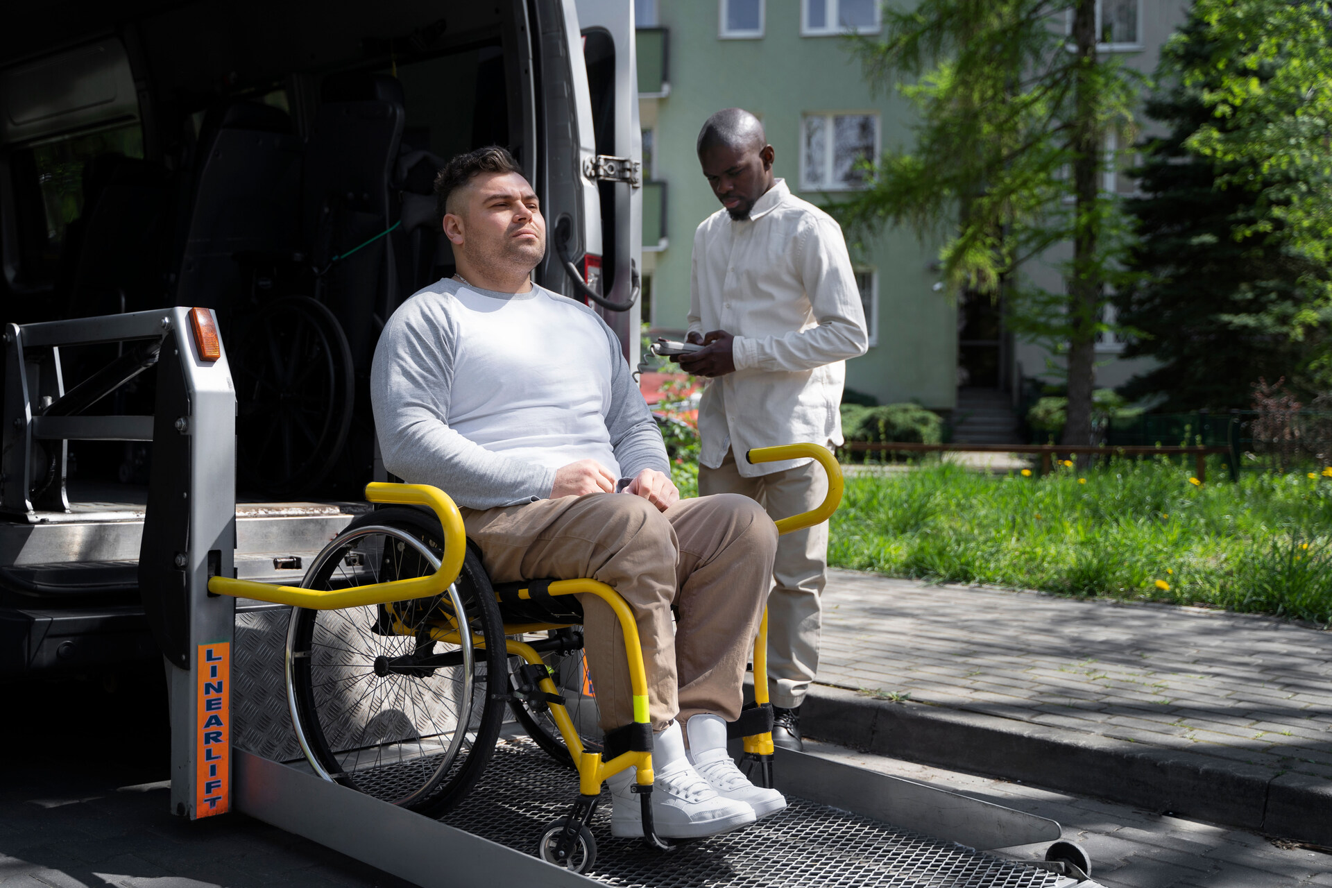 A man helping a wheelchair user off a vehicle